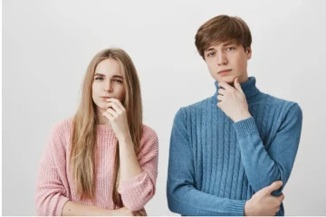 Girl and guy stand together, thinking, looking hesitant